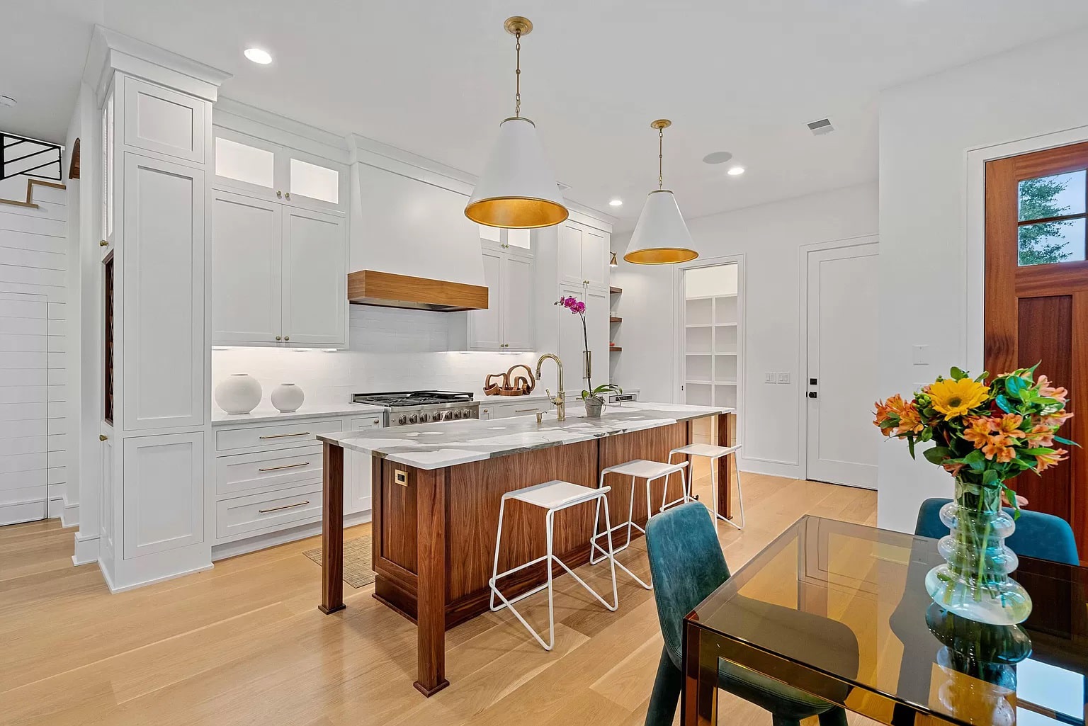 white kitchen with white shaker cabinets and gold accents featuring a white Hoodsly angled range hood with walnut band